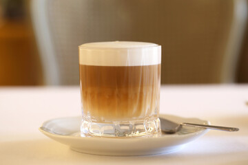a latte in a clear glass is on the table. breakfast in the restaurant. the latte is in the cafe.