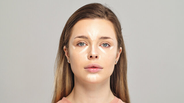 Foundation on the face of a female model. Cosmetic concealer base on a face. Professional makeup. Tutorial makeup master class