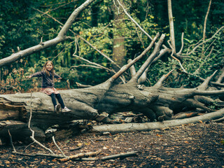 une jeune enfant joue heureuse en forêt sur un tronc d'arbre