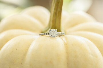 Engagement ring detail shot on a white pumpkin with a beautiful blurred background. Low depth of field.