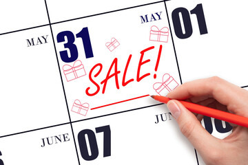 Hand writing text SALE and drawing gift boxes on calendar date May 31. Shopping Reminder