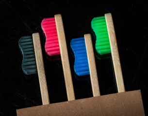 three coloured toothbrushes on a black background