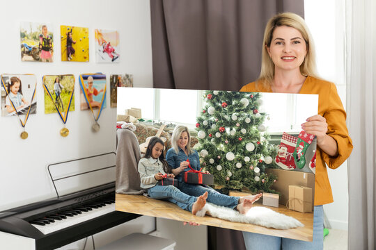 a woman holds a photo of Christmas on a photo canvas.