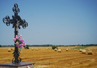 abgemähtes Heufeld in Polen mit christlichem Kreuz im Vordergrund