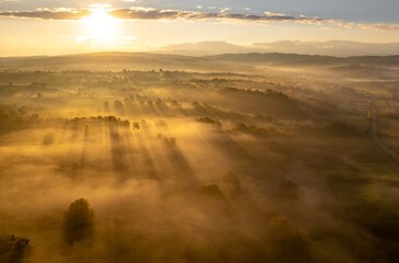 Fototapeta na wymiar Aerial colorful view of foggy autumn morning over hills and forests, in Soceni village, Romania. Captured from above, with a drone.