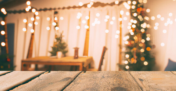 sfondo natalizio  di interno di abitazione con alberi di Natale sfocati  e in primo piano tavolo di legno ideale per presentazione prodotto