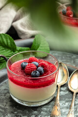Delicious italian dessert panna cotta with berry sauce on a dark background in small jars. place for text