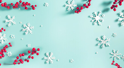 sfondo natalizio color azzurro  tiffany con copy space e bacche rosse e fiocchi di neve ai bordi © garpinina