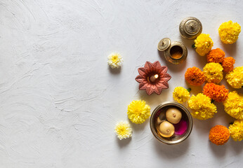 Marigold flowers scattered on white background with Indian traditional lamp, kumkum and sweet. Beautiful Hindu festive background or photo. View from above.