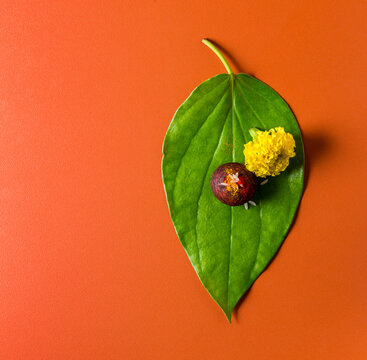 Betel nut and betel leaf placed in pooja and worshiped as a symbolic Ganesha in Hindu culture. Top view  of Betel nut, Paan and marigold flower shot from above on orange color background.