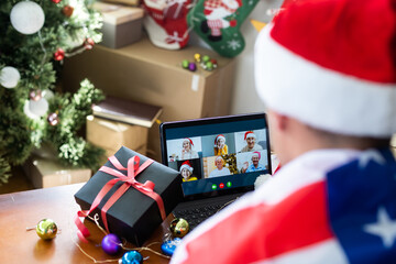 man are celebrating New Year, sitting, chatting and smiling near tablet in Santa's hats.