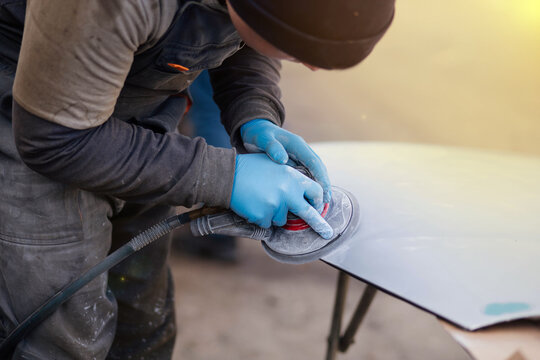 male craftsman polishes the paintwork surface of a car body element.