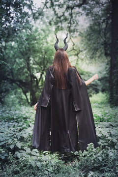 witch with horns Maleficent in the forest, back view