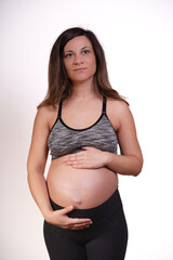 Thoughtful beautiful 30s-40s pregnant woman exercising and touching belly