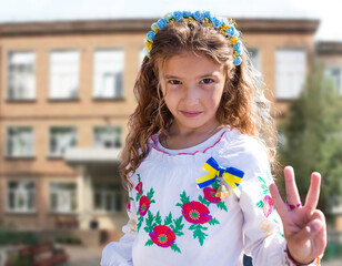 Ukrainian Schoolgirl in a wreath and embroidered shirt and with patriotic flowers against the war in Ukraine