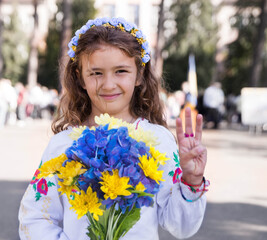 Ukrainian Schoolgirl in a wreath and embroidered shirt and with patriotic flowers against the war in Ukraine - 538408114
