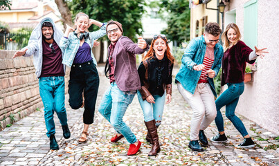 Millenial friends walking on funny mood at urban location - Multicultural lifestyle concept with...