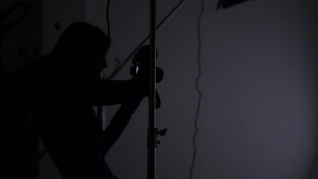 photographing a portrait of a beautiful sexy woman in the studio using a gabo mask and a white cyclorama. woman photographer on the silhouette takes pictures with a digital camera