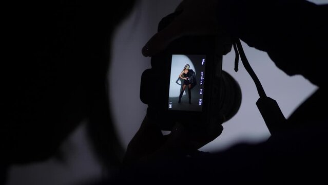 photographing a portrait of a beautiful sexy woman in the studio using a gabo mask and a white cyclorama. woman photographer on the silhouette takes pictures with a digital camera