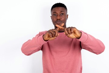 young handsome man wearing pink sweater over white background has rejection angry expression...