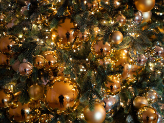 Obraz na płótnie Canvas Beautiful and lush Christmas tree decorated with glossy golden balls, festive Christmas background, without people