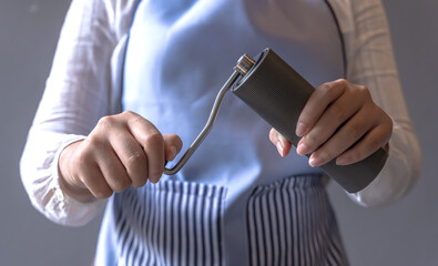 Barista woman holding manual coffee grinder preparing making coffee in coffeeshop, Coffee Barista Concept