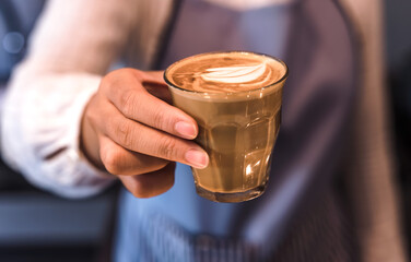 Fototapeta na wymiar Close up Barista hand holding glass of driping coffee in coffeeshop, Coffee Barista Concept