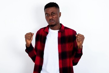 Irritated young handsome man wearing plaid red overshirt over white background blows cheeks with...