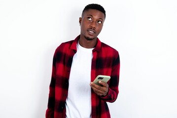 young handsome man wearing plaid red overshirt over white background holds mobile phone uses high speed internet and social networks has online communication. Modern technologies concept