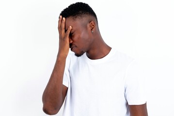 Fototapeta premium young handsome man wearing white T-shirt over white background with sad expression covering face with hands while crying. Depression concept.