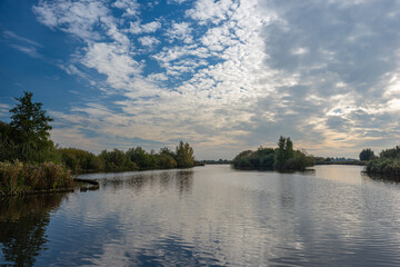 Altocumulus clouds are reflected in the calm water of recreation area Reeuwijkse Hout, close to Gouda, Holland.