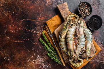 Whole Black tiger giant prawns shrimps in a skillet. Raw Seafood. Dark background. Top view. Free copy space
