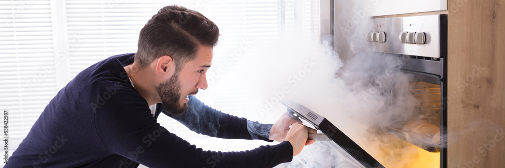 Wall mural shocked man looking at burnt cookies in oven