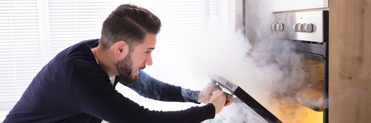 Shocked Man Looking At Burnt Cookies In Oven