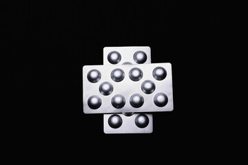 Set of medical tablets and pills in pharmaceutical blister pack on black