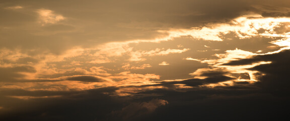 The sun breaking through the clouds during sunset creating a beam of orange light
