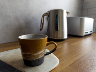 Coffee mug in modern trendy kitchen with grey cupboards and wood countertop