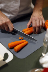 chef cortando zanahorias con cuchillo en tabla de corte