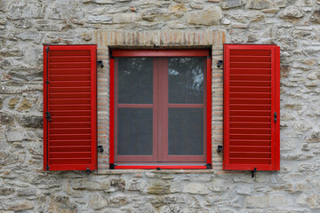 Window with open red shutter, brick stone house wall with rough and uneven surface, no person, 