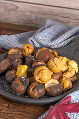 Roasted chestnuts in cast iron pan on an old board