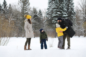 Happy family playing and laughing in winter outdoors in the snow. City park winter day.