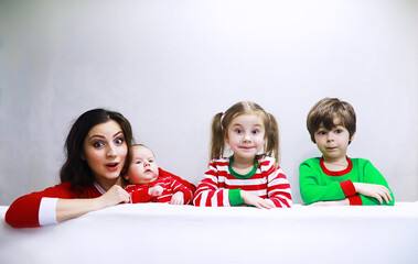 A family in striped pajamas is resting at home. Little children dressed as elves are lying on the sofa. Happy familywith banner.