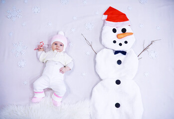 Newborn baby on a white background. Painting from white fabric. Snowman and baby. Christmas Holidays.
