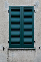 Fototapeta na wymiar window with shutters, green wooden shutter on a grey housewall as a background, no person