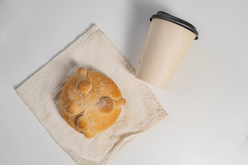 Traditional  mexican bread of the dead and paper cup of coffee on white table
