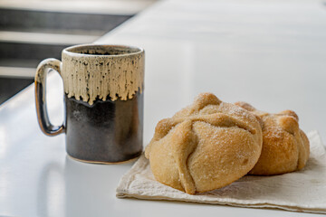 Traditional  mexican bread of the dead and cup of coffee on white table