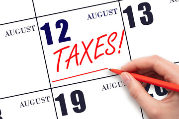 Hand drawing red line and writing the text Taxes on calendar date August 12. Remind date of tax payment