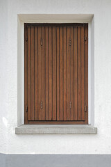 Old wooden window with shutters on a grey painted wall, vertical format