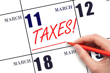 Hand drawing red line and writing the text Taxes on calendar date March 11. Remind date of tax payment