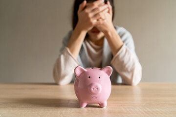 Sad girl with a piggy bank at home.